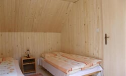 Pokoj s lůžky, nočními stolky a lampičkami v podkroví