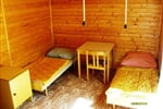 Interiér bungalovu s lůžky, stolkem a židlí