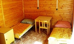 Interiér bungalovu s lůžky, stolkem a židlí