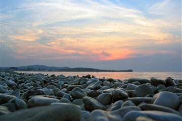 Západ slunce nad kamennou pláží