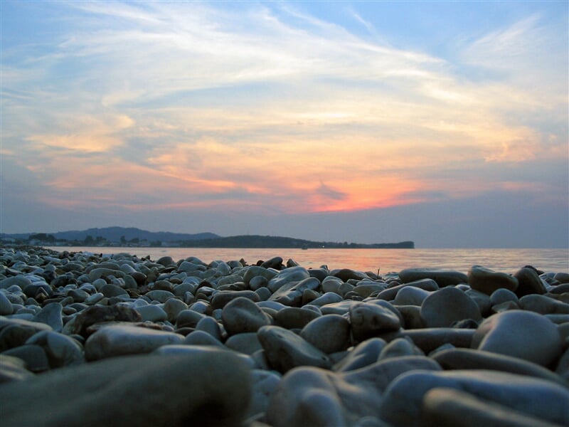 Západ slunce nad kamennou pláží
